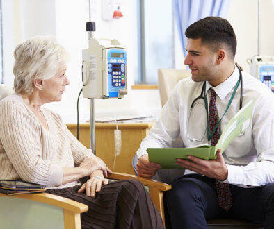 A Doctor Sitting Beside A Senior Woman Receiving Curative Treatment In Palliative Care Discussing Care Options