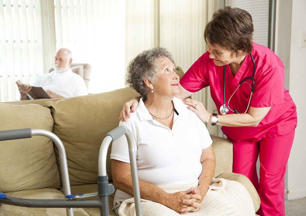how-dementia-hospice-care-works A Senior Woman Sitting On The Couch Being Comforted By A Hospice Caregiver Hospice Care For Dementia