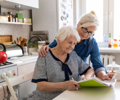 A Woman Helping Her Senior Mother Complete Paperwork For Her End-Of-Life Care Plan